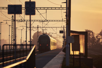 Railway at sunrise. passenger train leaving railroad station.