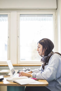 Side view of young female students using laptop in cafeteria at university