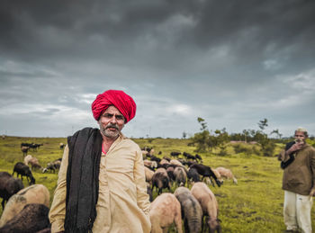 Portrait of man standing on field against sky
