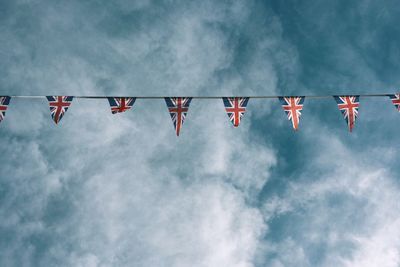 Low angle view of british flags bunting against cloudy sky