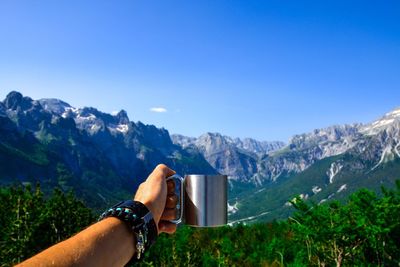 Close-up of hand holding mountain range against clear blue sky