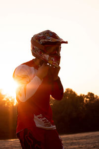 Midsection of woman holding umbrella against sky during sunset