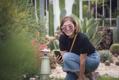 Portrait of young woman standing against plants