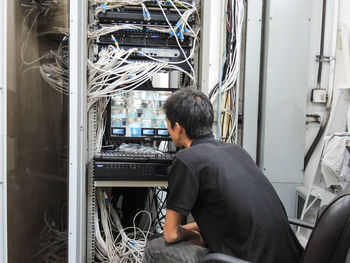 Rear view of man sitting in server room 