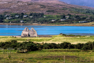 Scenic view of field by buildings against mountains