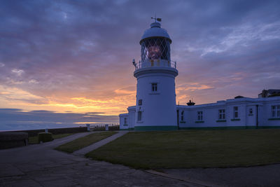 Pendeen lighthouse, cornwall with a sunrise behind it.
