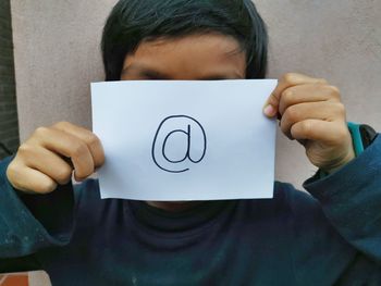 Close-up of boy holding paper with ampersand