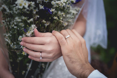 Cropped image of couple holding hands at field