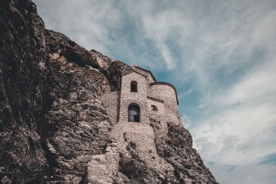 Low angle view of old building against cloudy sky