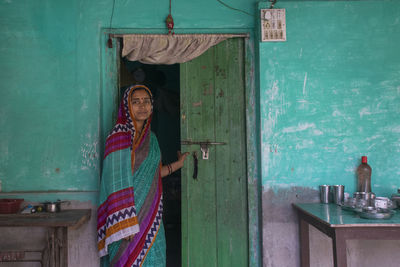 Portrait of indian woman wearing sari standing in front of door 