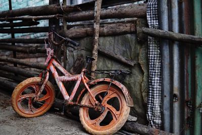 Abandoned bicycle parked against wood