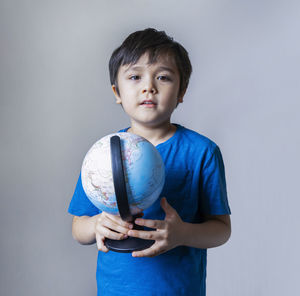 Portrait of boy standing against blue background