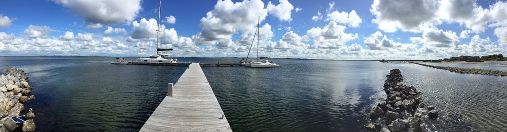 Panoramic view of sailboats at end of jetty