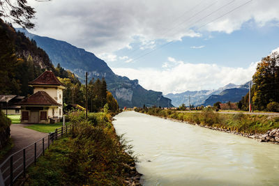 Scenic view of buildings and mountains at river against sky