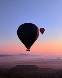 Hot air balloon flying over landscape against sky during sunset