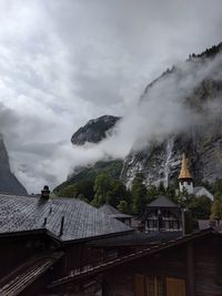 Houses by trees and mountains against sky