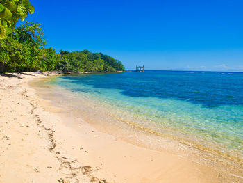 Scenic view of beach against clear blue sky