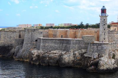 Buildings by sea against sky