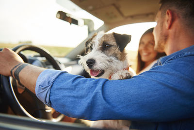 Smiling couple with dog in car