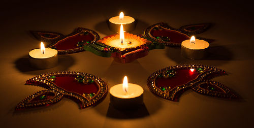 Close-up of lit diyas and tea light candles on table