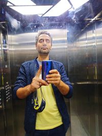 Young man looking through mobile phone while standing on window