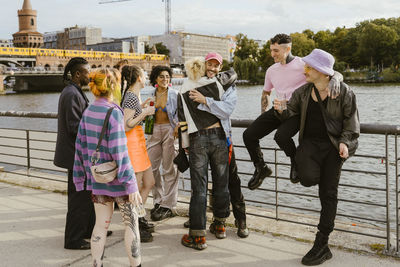 Happy non-binary friends greeting each other near on promenade in city