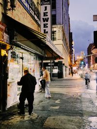 Rear view of people walking on street in city