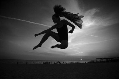 People jumping on beach against sky