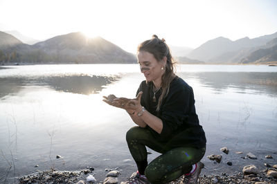 Woman putting mud on hands and face while enjoying outdoors in nature.