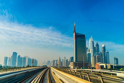 View of modern buildings in city against blue sky