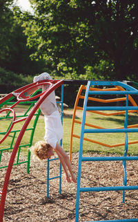 Woman hanging on outdoor play equipment at playground