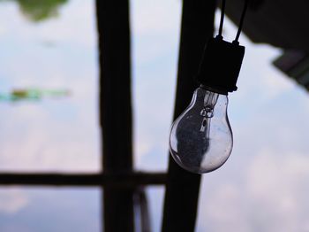 Close-up of light bulb hanging against window