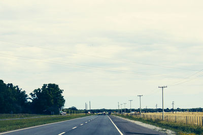 Road by trees against sky