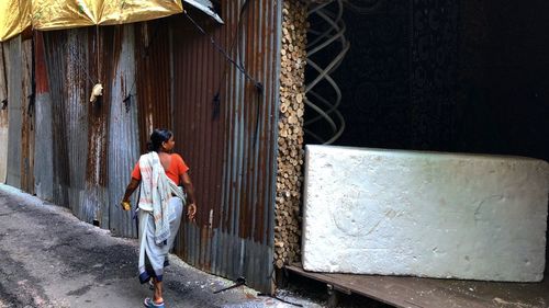 Rear view of man walking on footpath by building