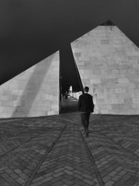 Rear view of man walking at split pyramid sculpture