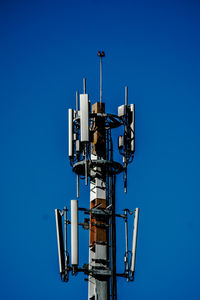 Low angle view of communications tower against clear blue sky