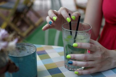 Cropped image of woman holding cocktail glass in restaurant