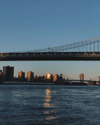 Bridge over sea against buildings in city against clear sky