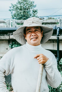 Portrait of man wearing hat standing against wall