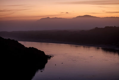 Calm lake along silhouette landscape