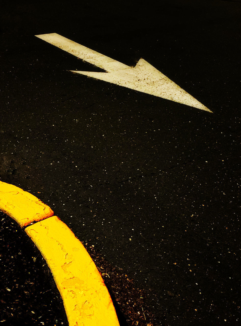 HIGH ANGLE VIEW OF ARROW SYMBOL ON ROAD