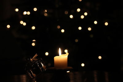 Close-up of burning candle on table at night