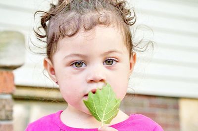 Close-up portrait of cute baby girl holding leaf