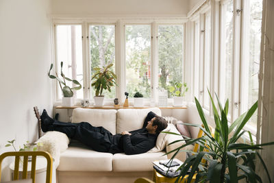 Side view of man sleeping on sofa in living room at home