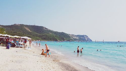 People at beach against clear sky