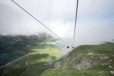 Overhead cable car over mountains against sky