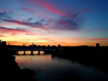 Silhouette of bridge over river against sky during sunset