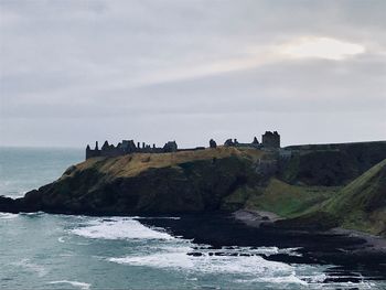 Scenic view of sea and cliff against sky