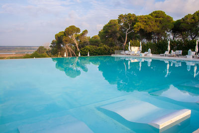 Swimming pool by trees against sky