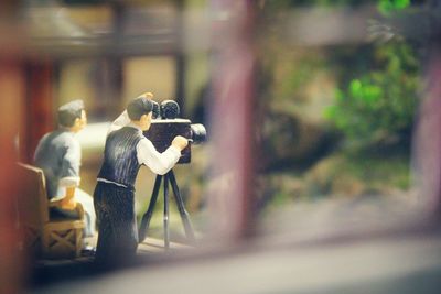 Figurines on window sill seen through metal grate